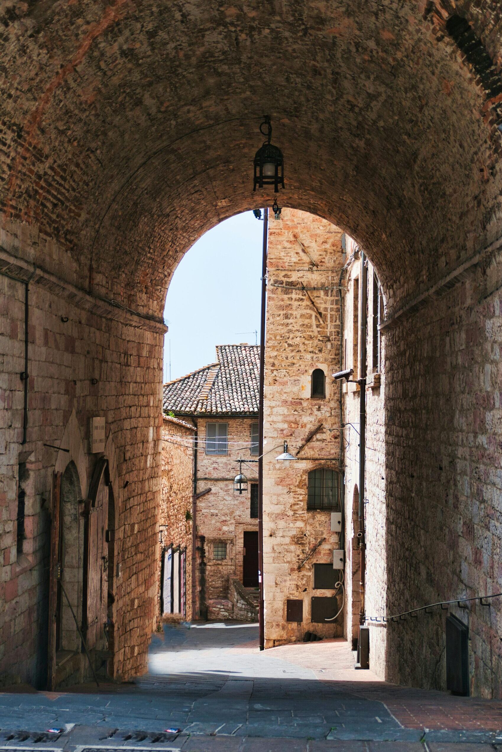 Explore a historic brick alleyway in Assisi, Umbria, Italy, showcasing rustic architecture.